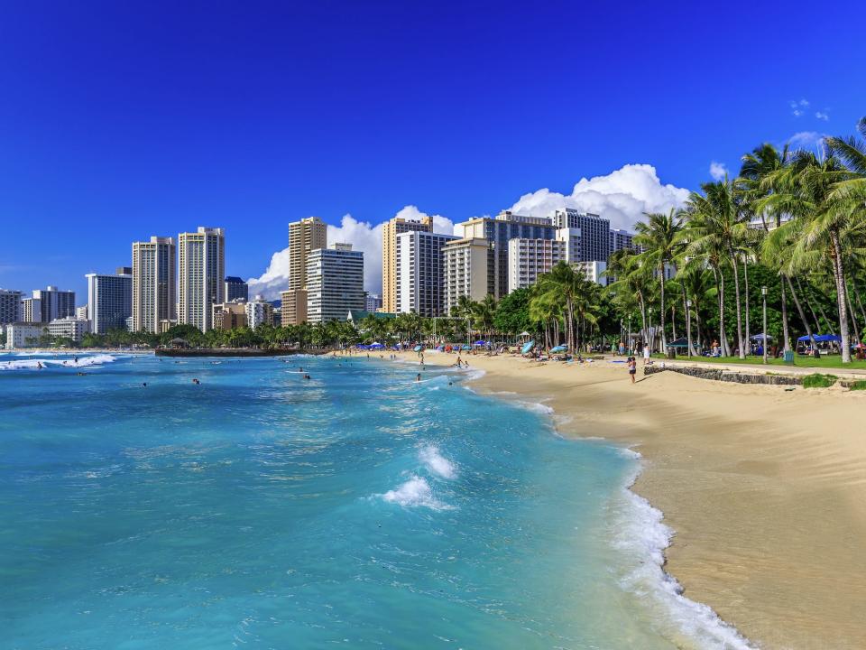 A view of Honolulu from the beach with buildings and palm trees