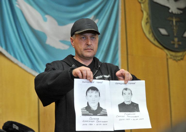 The seperatist leader of the eastern Ukrainian city of Slavyansk, Vyacheslav Ponomaryov, holds up pictures of two pro-Russia militants killed the day before in a gunbattle with unidentified attackers on April 21, 2014