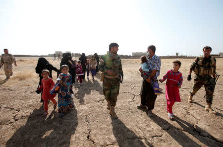 Kurdish Peshmerga fighters walk with displaced women and children after they escaped from the Islamic State-controlled village of Abu Jarboa, Iraq October 31, 2016. REUTERS/Azad Lashkari