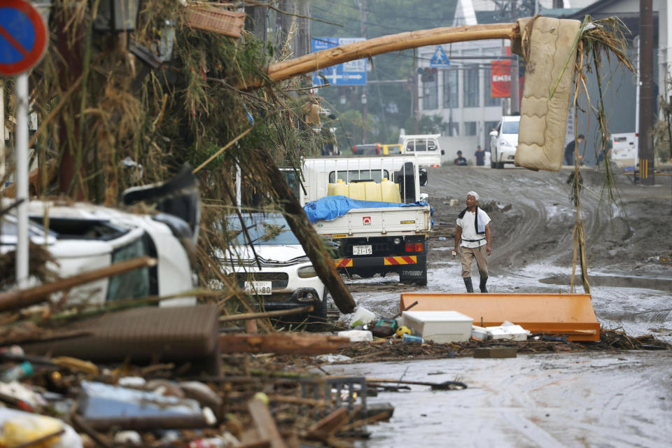 A man stands watch as debris and mud flown in a road in Hitoyoshi, Kumamoto prefecture, southwestern Japan, Sunday, July 5, 2020. Heavy rain in the Kumamoto region triggered flooding and mudslides Saturday and left dozens still being stranded at their homes and other facilities. (Takuto Kaneko/Kyodo News via AP)