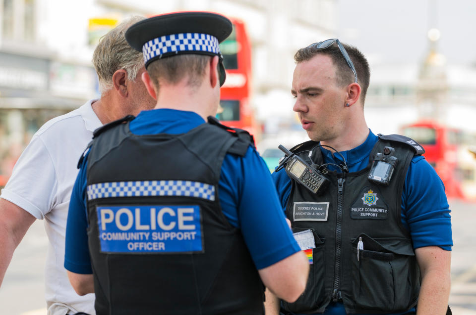 PCSOs (Police Community Support Officers) speaking to someone on the streets of Brighton, East Sussex, England, UK.