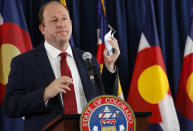 Colorado Governor Jared Polis holds up his face mask to make a point during a news conference on the state's efforts against the new coronavirus, Tuesday, July 21, 2020, in Denver. (AP Photo/David Zalubowski)