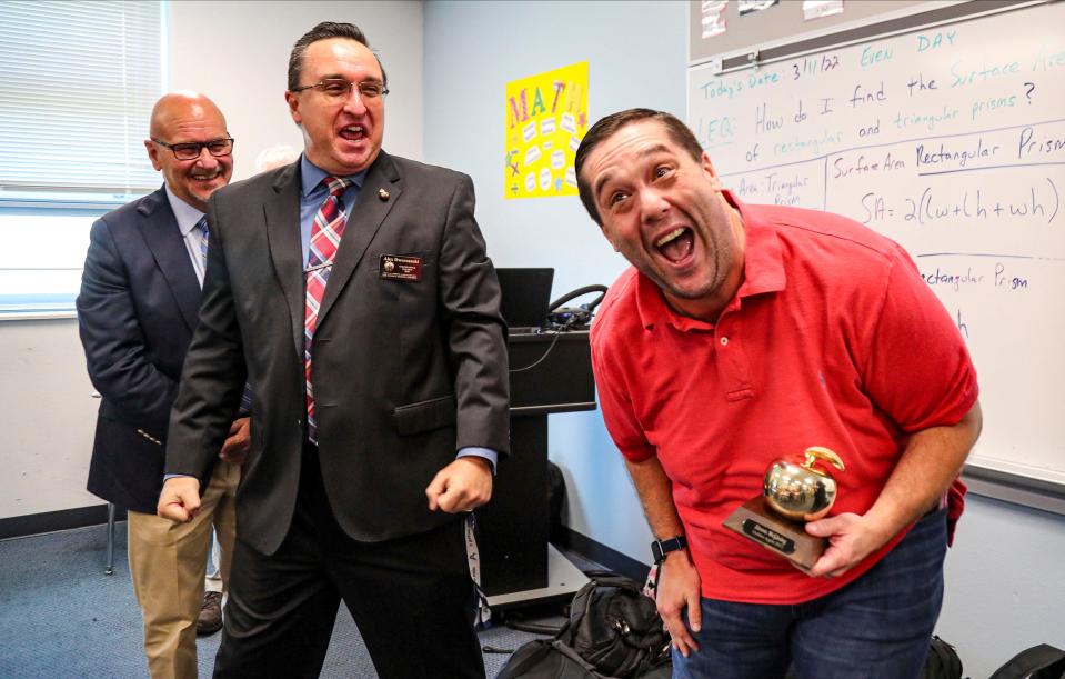 Harns Marsh Middle School seventh grade civics teacher Steven McGinley, right, celebrates with his principal Alex Dworzanski, center, after he was awarded the 2021-2022 Golden Apple Award on Friday, March 11, 2022, in Lehigh Acres.