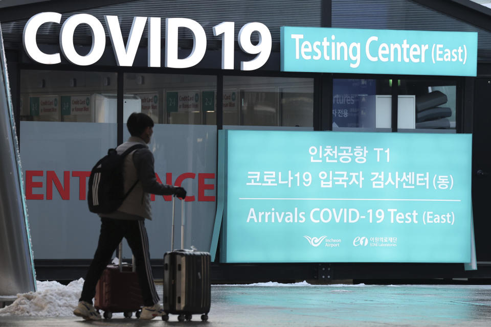 A traveler walks near a banner for the coronavirus testing center at the Incheon International Airport in Incheon, South Korea, Friday, Dec. 30, 2022. South Korea on Friday announced that it will require travelers from China to show negative PCR test results within 48 hours or rapid antigen tests within 24 hours of their departures, beginning Jan. 5. (Ryu Young-suk/Yonhap via AP)