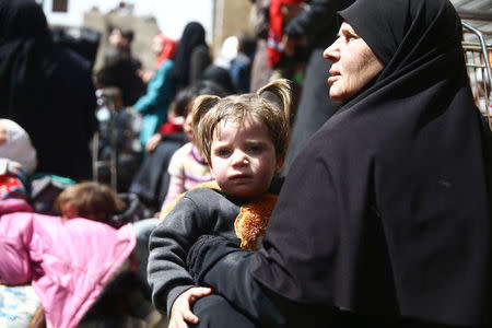 A woman holds a child during evacuation from the besieged town of Douma, Eastern Ghouta, in Damascus, Syria March 22, 2018. REUTERS/Bassam Khabieh