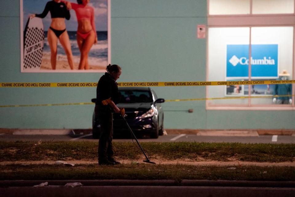 A law enforcement officer uses a metal detector on the ground to look for evidence outside Surf Style in Biloxi after a chaotic shooting during Black Spring Break that left one police officer injured on Sunday, April 16, 2023.