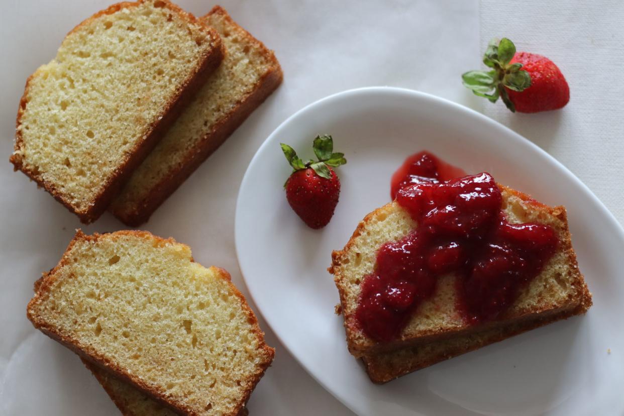 Sour cream pound cake along with a slice of pound cake with strawberry sauce spread. Shot on white background