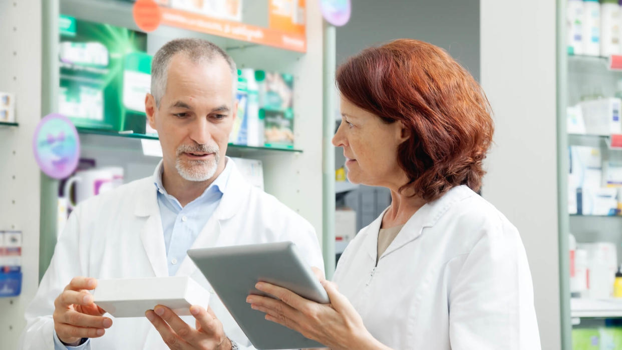 Two pharmacists, mature man and woman, working.