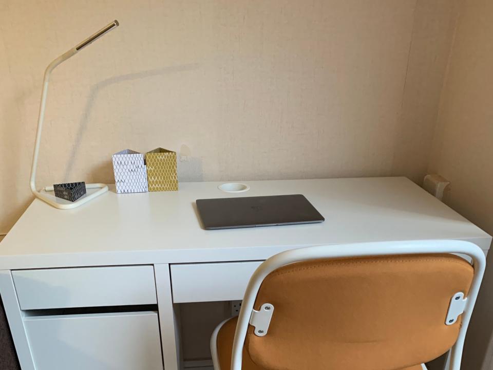 Image of a white desk with chair and laptop.