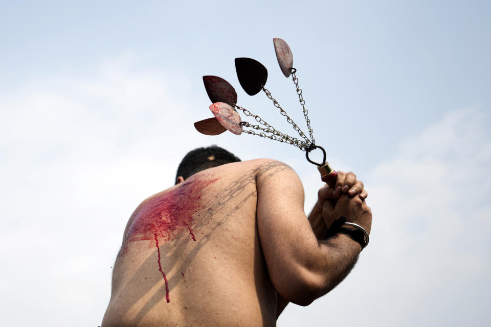 A Shiite Muslim flagellates himself with knifes on chains during a procession to mark Ashoura, in Islamabad, Pakistan, Friday, July 28, 2023. Ashoura is the Shiite Muslim commemoration marking the death of Hussein, the grandson of the Prophet Muhammad, at the Battle of Karbala in present-day Iraq in the 7th century.(AP Photo/Rahmat Gul)
