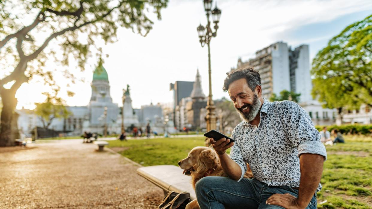 Man looking down at phone sitting next to his dog