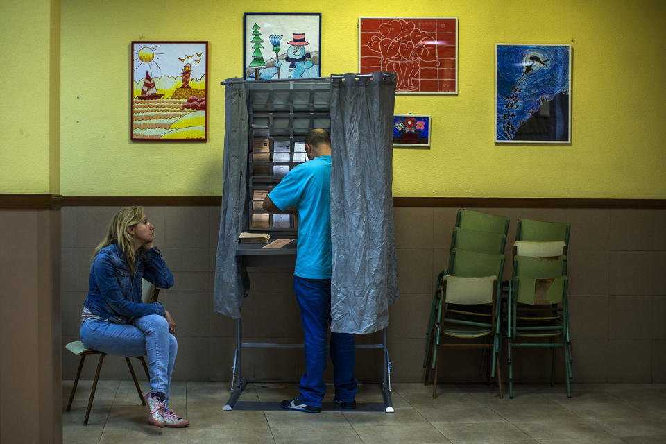 <p>A man prepares to vote as his partner and two children wait at a polling station in Madrid, May 24, 2015. (AP Photo/Andres Kudacki) </p>