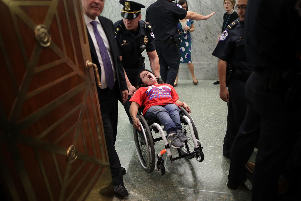 <p>U.S. Capitol Police remove a protester in a wheel chair from a Senate Finance Committee hearing about the proposed Graham-Cassidy Healthcare Bill in the Dirksen Senate Office Building on Capitol Hill September 25, 2017 in Washington, DC. Demonstrators disrupted the hearing to protest the legislation, the next in a series of Republican proposals to replace the Affordable Care Act, also called Obamacare. (Photo: Chip Somodevilla/Getty Images) </p>