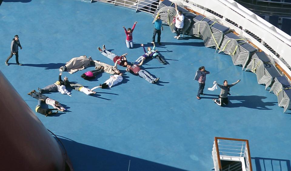 FILE - In this Feb. 14, 2013, file photo, passengers spell out the word "HELP" aboard the disabled Carnival Lines cruise ship Triumph as it is towed to harbor off Mobile Bay, Ala. About three dozen passengers aboard the ill-fated cruise liner have filed a lawsuit in Miami hoping to collect thousands of dollars as a result of lingering medical and mental issues they claim were caused by their nightmarish experience. (AP Photo/Gerald Herbert, File)