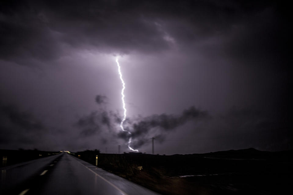 Lightning strikes ground on the outskirts of the village of Campillos, Spain, where heavy rain and floods caused much damage and the death of a firefighter according to Spanish authorities Sunday, Oct. 21 2018. Emergency services for the southern region of Andalusia say that the firefighter went missing when his truck overturned on a flooded road during heavy rain that fell through the night, and his body was found after a search Sunday morning. (AP Photo/Javier Fergo)