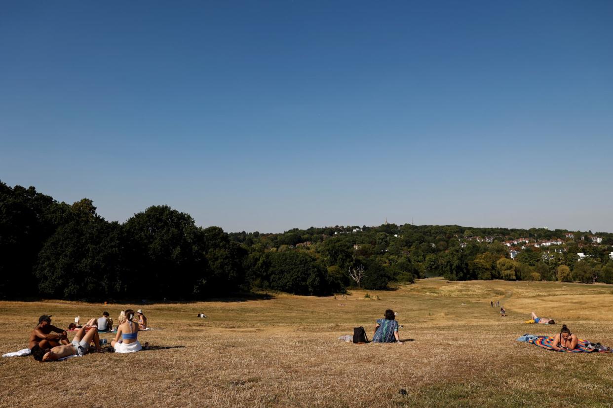 Des personnes s'assoient sur l'herbe séchée dans le parc de Hampstead Heath, à Londres, le 13 août 2022. - CARLOS JASSO / AFP