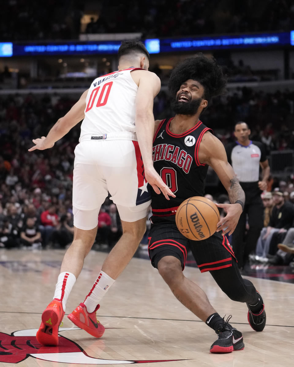 Chicago Bulls' Coby White (0) collides with Washington Wizards' Tristan Vukcevic during the second half of an NBA basketball game Monday, March 25, 2024, in Chicago. (AP Photo/Charles Rex Arbogast)