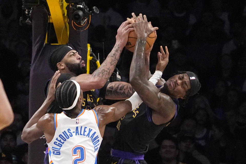 Los Angeles Lakers forward Anthony Davis, center, grapples for a rebound with Oklahoma City Thunder guard Shai Gilgeous-Alexander, left, and forward Jarred Vanderbilt during the first half of an NBA basketball game Monday, Jan. 15, 2024, in Los Angeles. (AP Photo/Mark J. Terrill)