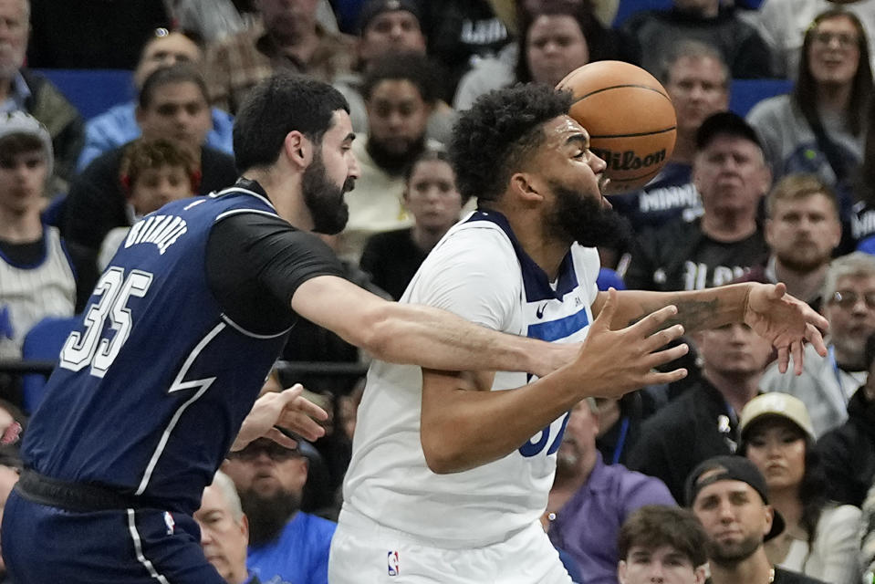 Minnesota Timberwolves center Karl-Anthony Towns, right, momentarily loses control of a rebound as he is guarded by Orlando Magic center Goga Bitadze (35) during the first half of an NBA basketball game, Tuesday, Jan. 9, 2024, in Orlando, Fla. (AP Photo/John Raoux)