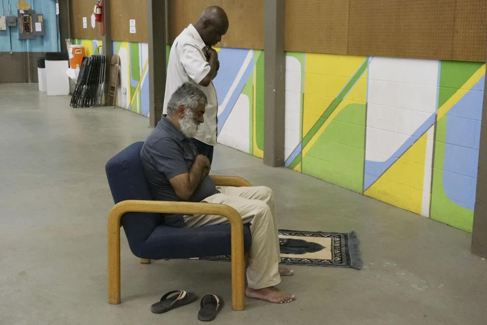 Building Blocks of Islam volunteers Mashood Yunus, seated, and Mahmoud Jawara pray in an upstairs room in the education building where their booth operates during the Minnesota State Fair in Falcon Heights, Minn., on Thursday, Aug. 24, 2023. Yunus helped start the organization to combat misinformation about Islam. (AP Photo/Giovanna Dell'Orto)