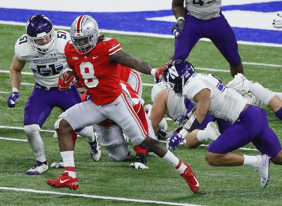 Ohio State Buckeyes running back Trey Sermon (8) stiff arms Northwestern Wildcats defensive back JR Pace (5) as he rushes upfield during the third quarter of the Big Ten Championship football game at Lucas Oil Stadium in Indianapolis on Saturday, Dec. 19, 2020. Ohio State won 22-10.