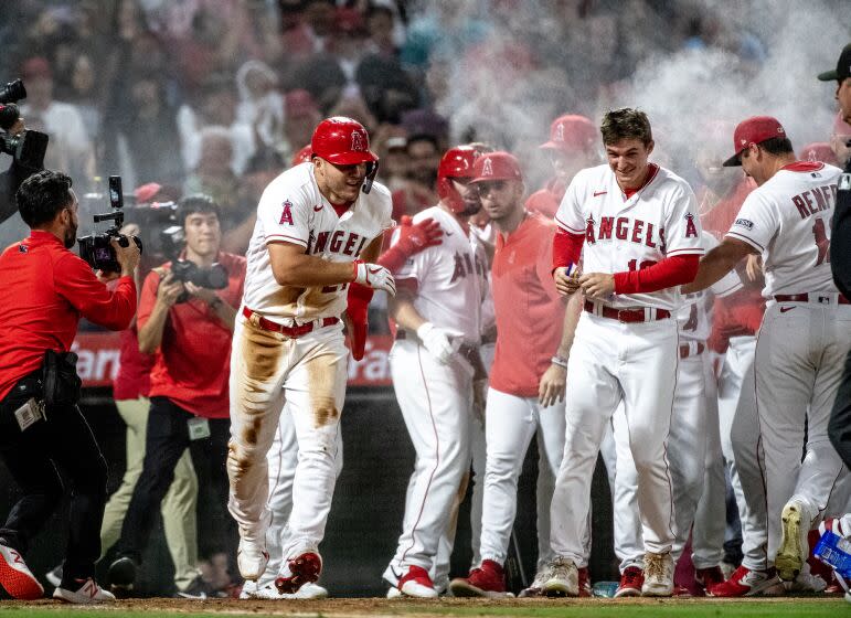 ANHEIM, CA - JUNE 26, 2023: Angels teammates swarm center fielder Mike Trout (27), left, and spray him with powder after he scored the winning run on a wild pitch by Chicago White Sox relief pitcher Aaron Bummer (39) in the ninth inning at Angel Stadium on June 26, 2023 in Anaheim, California.  (Gina Ferazzi / Los Angeles Times)