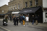 People queue up and wait for their takeaway orders outside the Climpson & Sons specialty coffee cafe, which is only allowed to open for takeaway orders during England's second coronavirus lockdown, on Broadway Market in Hackney, east London, Tuesday, Nov. 17, 2020. Climpsons struggled to adapt to the coronavirus at first, with the cafe shut, and wholesale business almost completely wiped out, but now they often serve more take-away coffees than before the pandemic.(AP Photo/Matt Dunham)