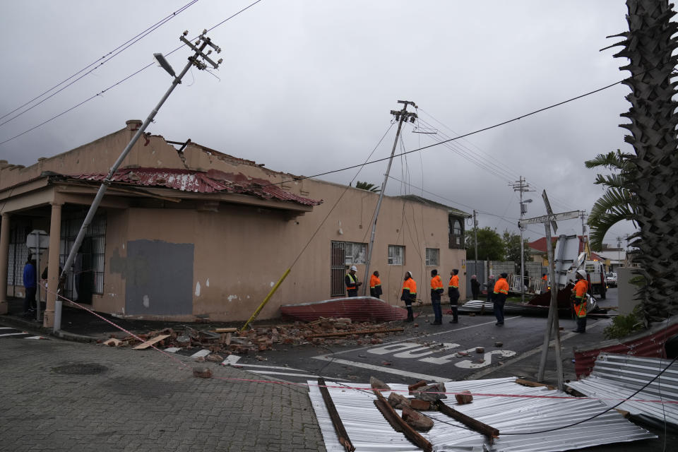 Rescue workers among damaged buildings in the Wynberg neighborhood of Cape Town, South Africa, Thursday, July 11, 2024. The area was hit overnight during strong winds that blew off roofs, destroyed parts of houses and other buildings, and brought down electricity poles. (AP Photo/Nardus Engelbrecht)