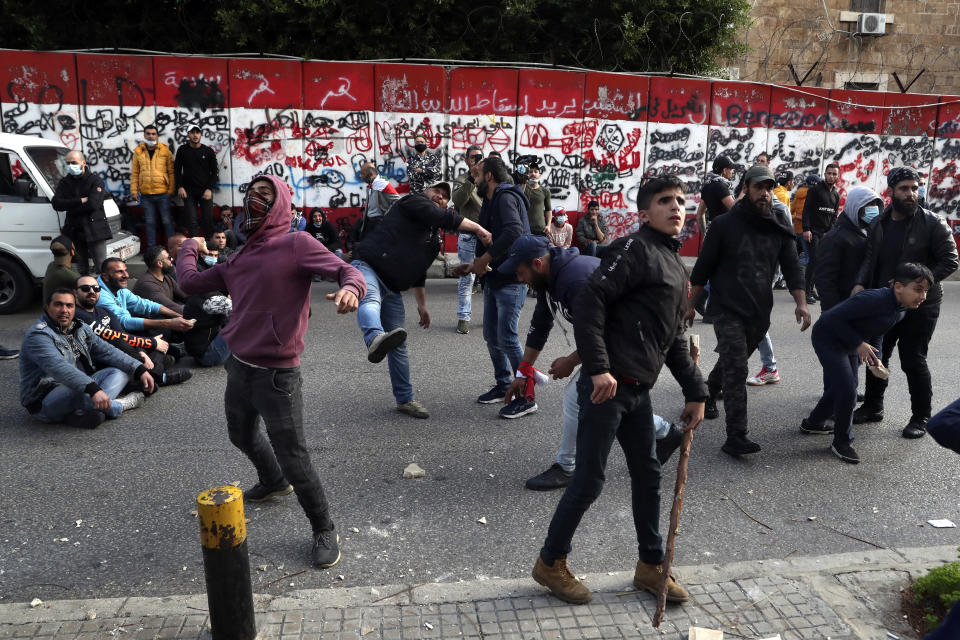 Protesters throw stones towards the central bank building, during a protest in Beirut, Lebanon, Saturday, March. 13, 2021. Riot police fired tear gas to disperse scores of people who protested near parliament building in central Beirut Saturday amid deteriorating economic and financial conditions and as the local currency hit new low levels. (AP Photo/Bilal Hussein)