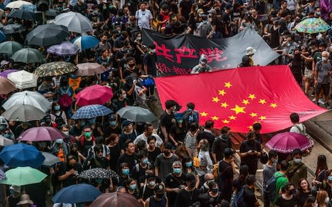 Protesters marched with a banner that used the stars of the Chinese national flag to depict a Nazi swastika, the day after Beijing carried out anti-riot drills in a neighbouring mainland city - Credit: Anthony Wallace/AFP