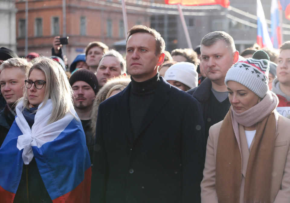 Alexei Navalny, center, looking somber but resolute, and his wife Yulia, in wool hat, surrounded by demonstrators.