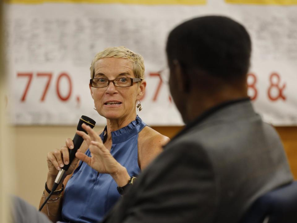 Jane McAlevey, left, holds a microphone as a man in the foreground listens