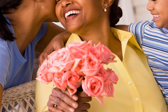 <p>Ariel Skelley/Getty</p> A mother receiving flowers from her kids (stock image)