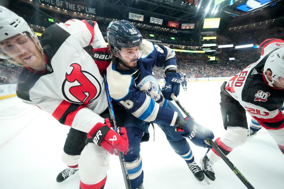 Blue Jackets forward Kirill Marchenko fights for a puck with Devils Dougie Hamilton (7) and Michael McLeod.