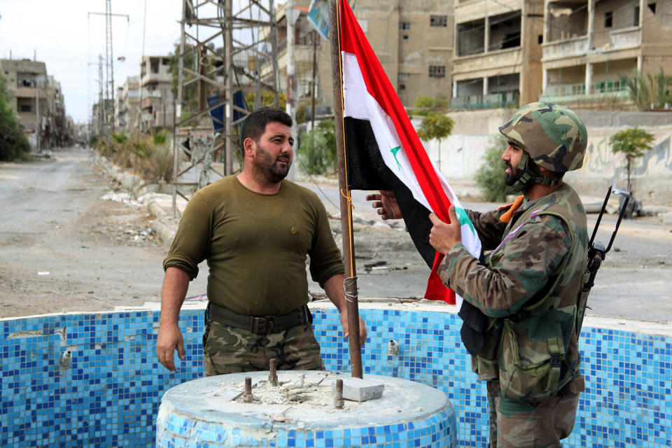 FILE - In this Friday, Nov. 8, 2013 file photo, released by the Syrian official news agency SANA, Syrian army soldiers place a national flag at a square in the Sabina suburb Syrian troops captured, south of Damascus, Syria. Two years ago, it seemed almost inevitable that President Bashar Assad would be toppled. Almost no one thinks that now. As he prepares for elections through which he is set to claim another seven-year mandate for himself, the momentum in the civil war is clearly in Assad's favor. (AP Photo/SANA, File)