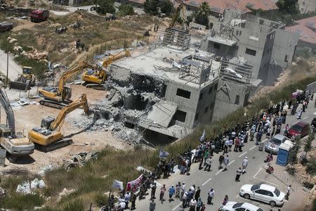 Israeli paramilitary police and Jewish settlers stand near two partially-built dwellings during their demolition in the West Bank Jewish settlement of Beit El near Ramallah July 29, 2015. REUTERS/Baz Ratner