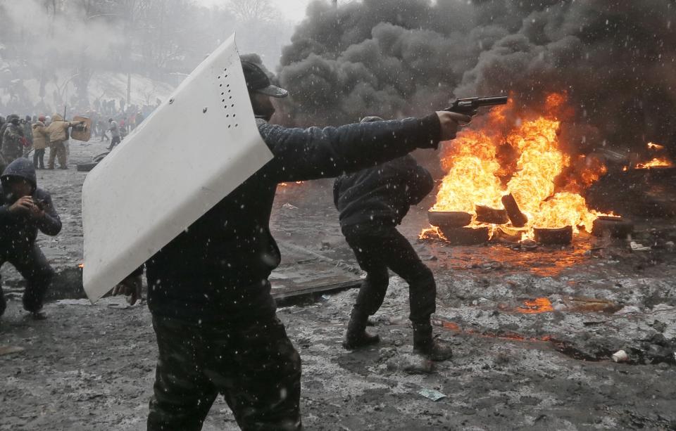 FILE - In this file photo taken on Wednesday, Jan. 22, 2014, A protester points a handgun during a clash with police in central Kiev, Ukraine. Three people have died in clashes between protesters and police in the Ukrainian capital Wednesday, according to medics on the site, in a development that will likely escalate Ukraine's two month-long political crisis. The mass protests in the capital of Kiev erupted after Ukrainian President Viktor Yanukovych spurned a pact with the European Union in favor of close ties with Russia, which offered him a $15 billion bailout. (AP Photo/Efrem Lukatsky, file)