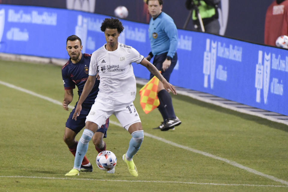 New England Revolution forward Tajon Buchanan (17) works for control of the ball against Chicago Fire defender Jonathan Bornstein (3) during the first half of an MLS soccer match in Chicago, Saturday, April 17, 2021. (AP Photo/Mark Black)