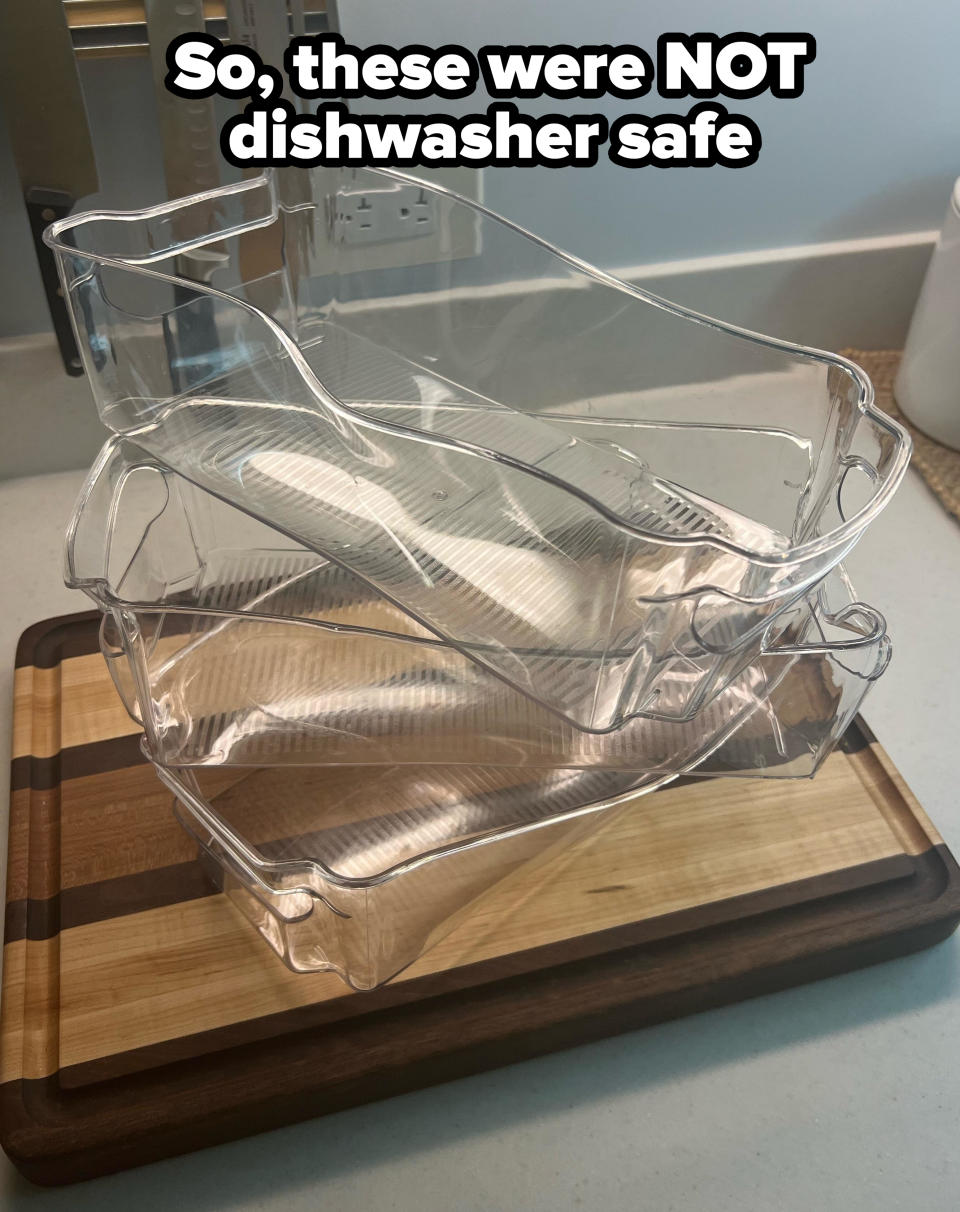 Two transparent plastic refrigerator shelves are stacked on top of each other on a cutting board in a kitchen