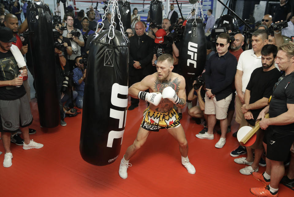 Conor McGregor hits a heavy bag while surrounded by media and supporters during a workout on Aug. 11. (AP)