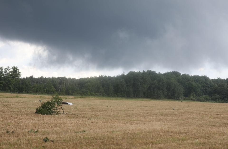 Storm clouds continued to move through the East Eden area as residents cleaned up after a tornado touched down on East Eden Road. Debris was scattered on a field nearby on Schientzius Road.