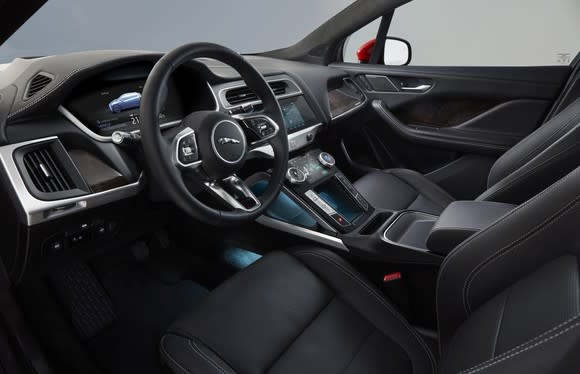 A view of an I-Pace's front seats and dashboard, showing black leather, dark wood, and brushed-metal trim.