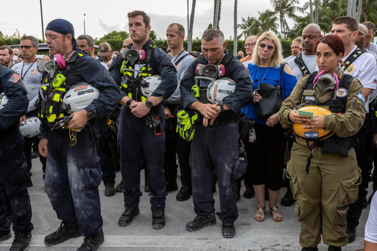 Members of a search and rescue team stand in front of the rubble that once was Champlain Towers South during a prayer ceremony in Surfside, Fla. on Wednesday, July 7, 2021.