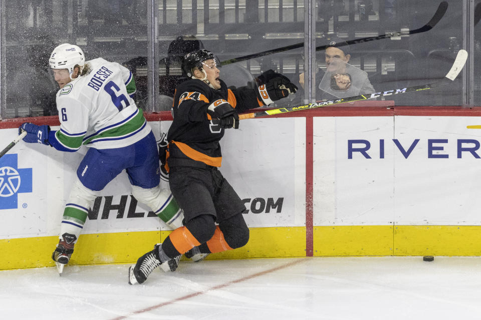 Vancouver Canucks right wing Brock Boeser (6) and Philadelphia Flyers defenseman Nick Seeler (24) crash into the boards while trying to control the puck during the second period of an NHL hockey game, Saturday, Oct. 15, 2022, in Philadelphia. (AP Photo/Laurence Kesterson)