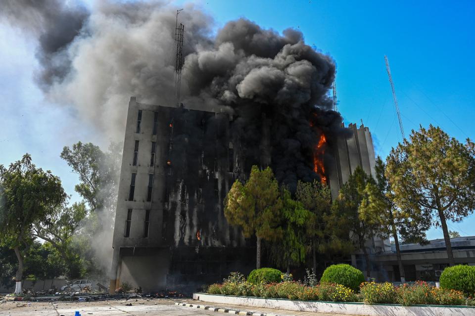 Black smokes billows from a building set ablaze by Pakistan Tehreek-e-Insaf (PTI) party activists and supporters of former Pakistani Prime Minister Imran during a protest against his arrest, in Peshawar, May 10, 2023. / Credit: ABDUL MAJEED/AFP/Getty