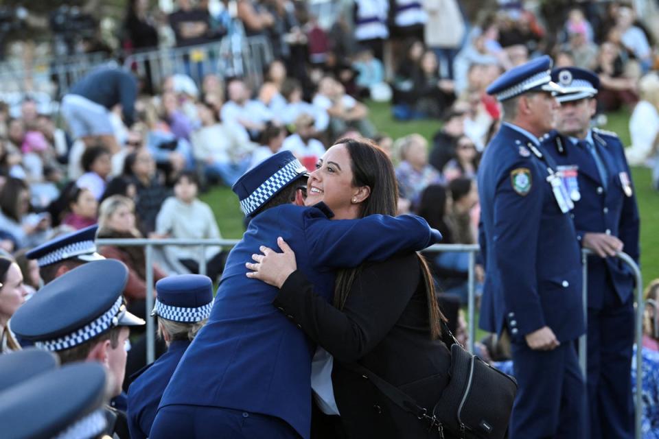 A woman hugs a police officer during the Community Candlelight Vigil (REUTERS)