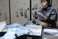 In this image from video, Yoshiko Ogura, 73, sorts out indigo dyed silk masks she produces at her house in Minamisoma, Fukushima Prefecture, northeastern Japan, on Feb. 20, 2021. After the Fukushima nuclear plant disaster a decade ago, nearby farmers weren't allowed to grow crops for two years because of radiation. After the restriction was lifted, two farmers in the town of Minamisoma found an unusual way to rebuild their lives and help their destroyed community. Kiyoko Mori and Ogura planted indigo and soon began dying fabric with dye produced from the plants. (AP Photo/Chisato Tanaka)