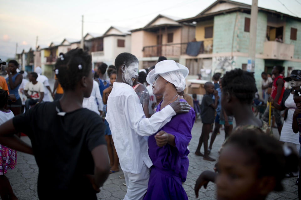 In this Nov. 1, 2018 photo, voodoo believers who are supposed to be possessed with Gede spirit dance in the middle of the street during the annual Voodoo festival Fete Gede at Cite Soleil Cemetery in Port-au-Prince, Haiti. The characteristics of this traditional celebration, the flamboyant customes and the white-powdered faces of the priests in trance inspired some of the first Hollywood stories about zombies. ( AP Photo/Dieu Nalio Chery)