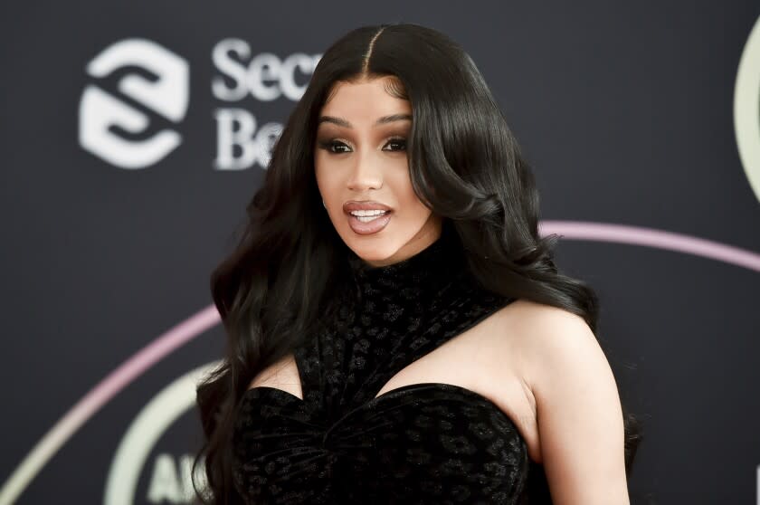 Cardi B posing in a black dress