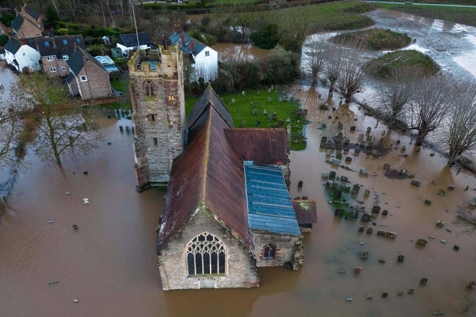Worcester, January 3rd 2024 - St. Deny's Church and graveyard in the English hamlet of Severn Stoke which has been completely cut off by flooding after the River Severn burst its banks due to continued rainfall from Storm Henk. The graveyard at St. Deny's church is also under water. The Rose and Crown pub could be seen pumping water out as it battled to stay dry with their homemade flood defences. - Credit: Stop Press Media/Alamy Live News